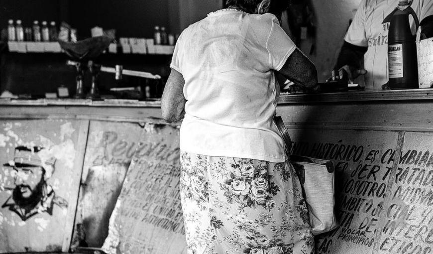 Anciana compra alimentos normados en una bodega en Cuba. Frase de Fidel Castro en el mostrador. Foto: Bradys Barreras.