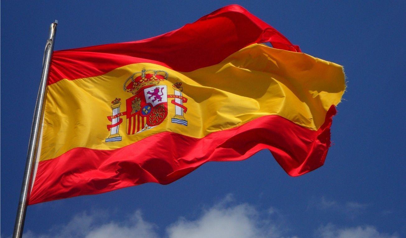 Bandera española ondeando, cielo azul, nubes, España. Foto: Canva.