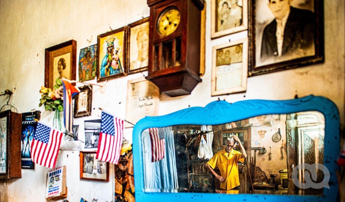 Pared, reloj, anciano, cuadros, banderitas, Cuba, Estados Unidos. Foto: David Estrada.