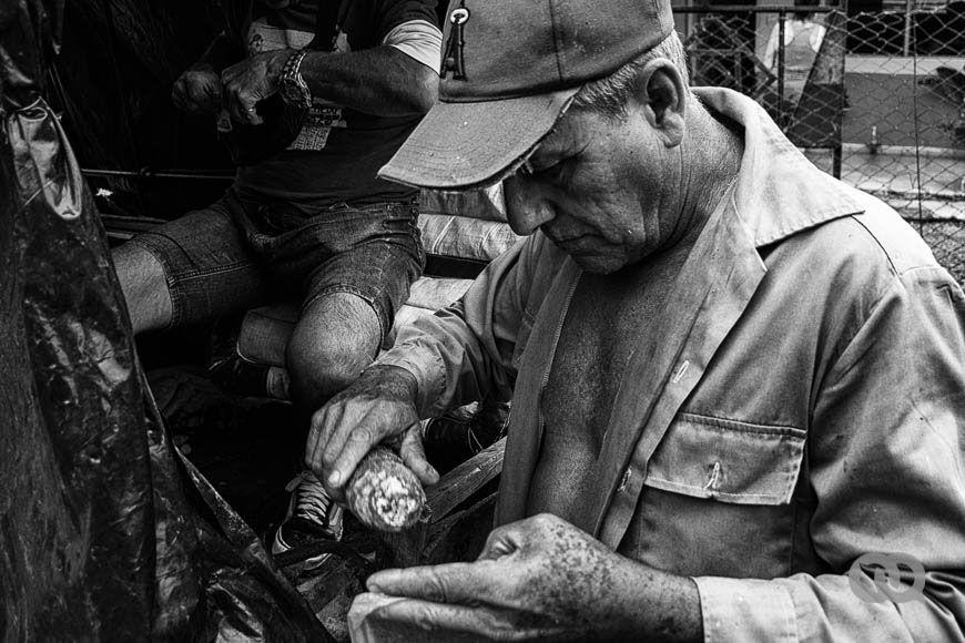 Ricardo compra yucas a un vendedor ambulante. Una vecina se acerca con la ilusión de comprar cebollas y se aleja maldiciendo el precio (Foto: Sadiel Mederos Bermúdez). 