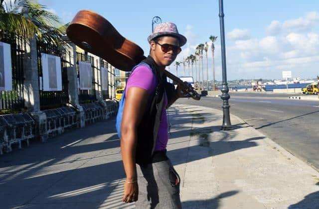 turismo_en_cuba_-joven-con-guitarra-en-el-malecón-de-La-Habana-economía.jpg