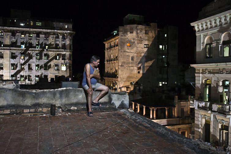 Hombre sentado en la azotea de edificio en La Habana, de noche. Patricio Wood en "Últimos días en La Habana".